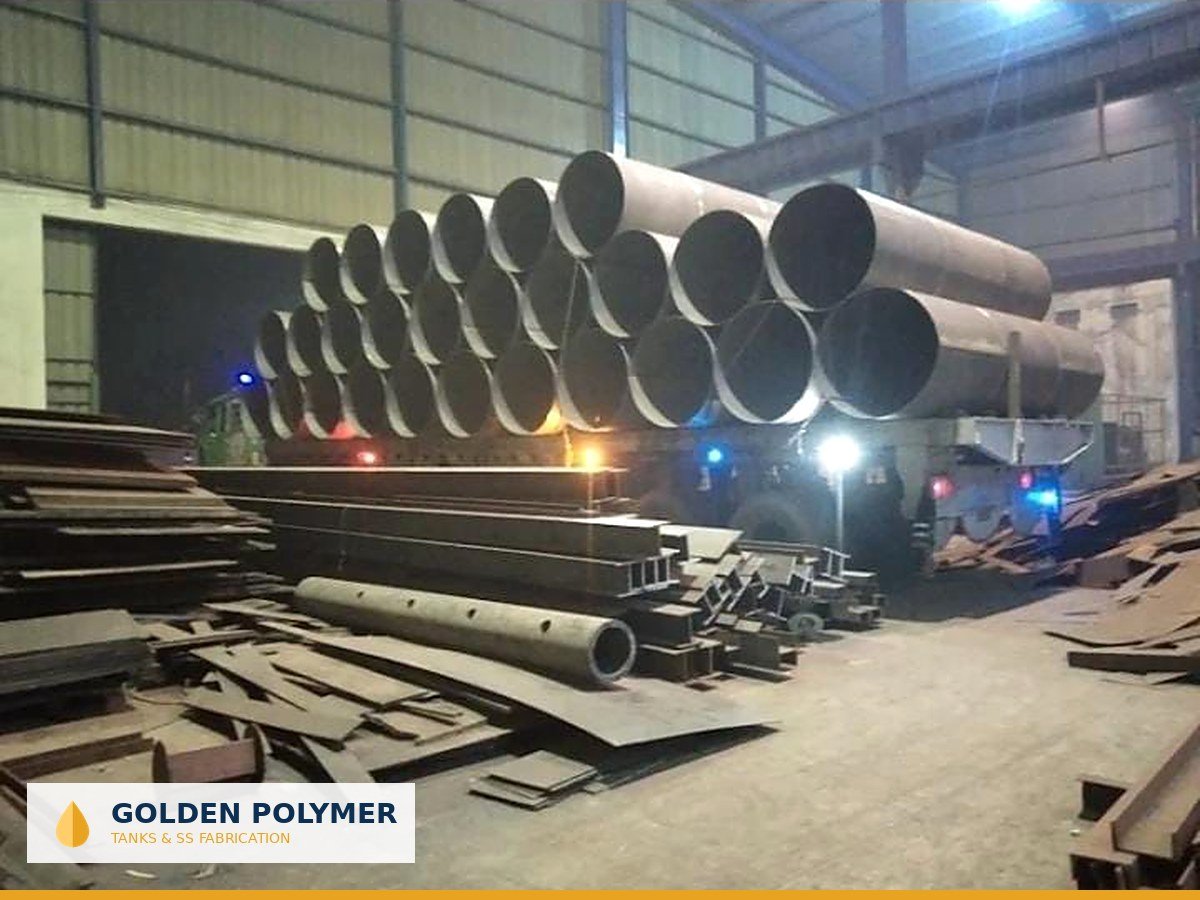 Stack of large-diameter rolled steel pipe sections in the workshop